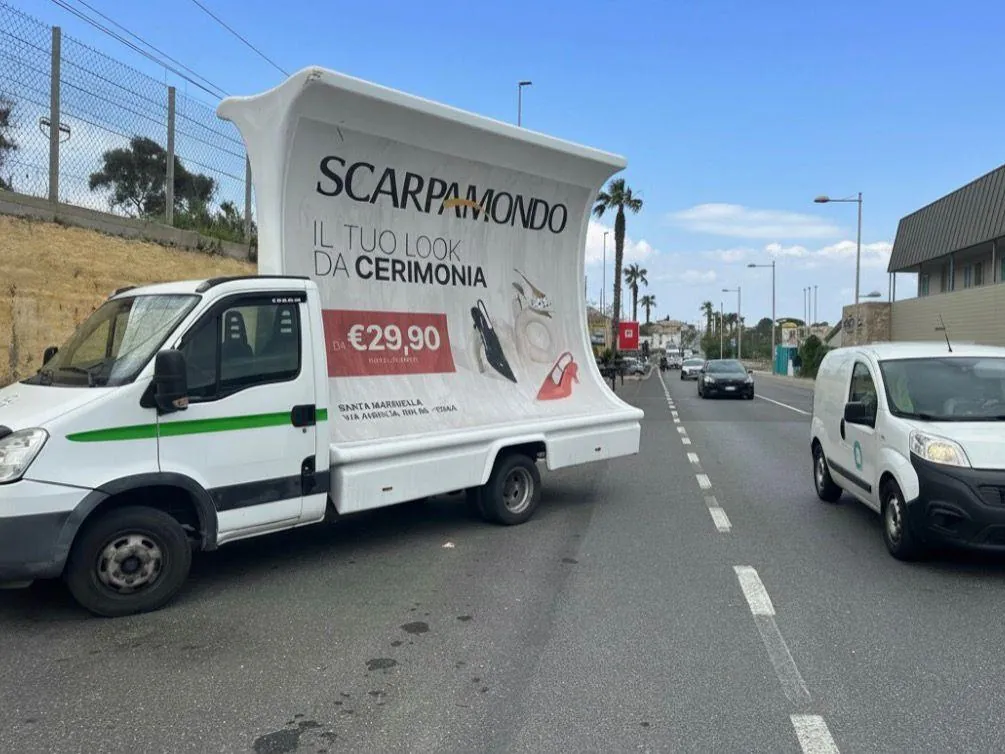 Camion vela di M.A.T. Advertising con manifesto pubblicitario in strada